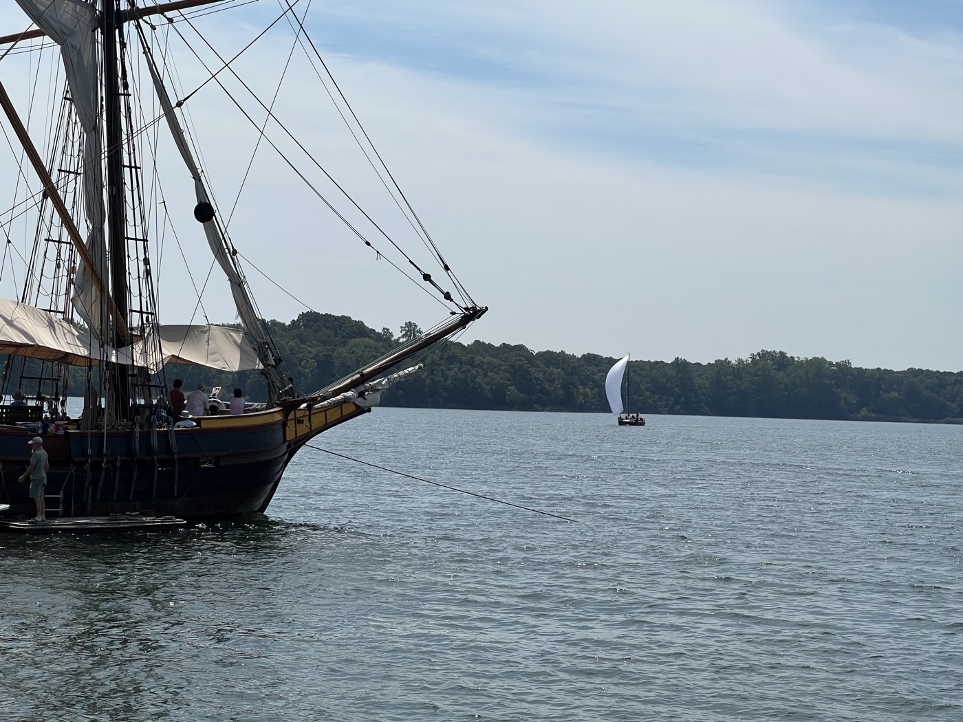 A tall ship at anchor on the Chesapeake with a small sloop sailing past